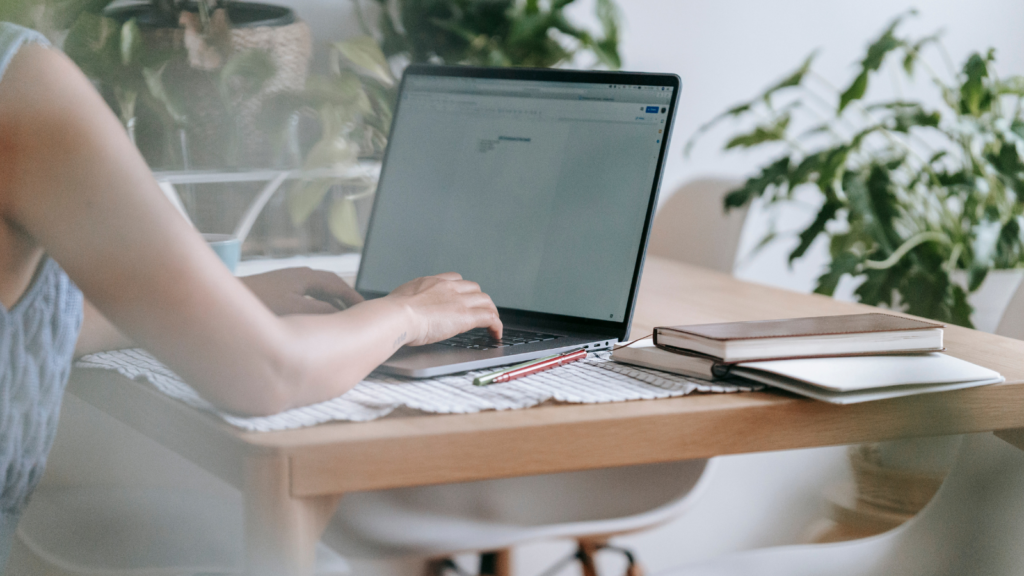 Stock photo from pexels by Teona Swift of a woman typing on a laptop sitting at a wooden desk