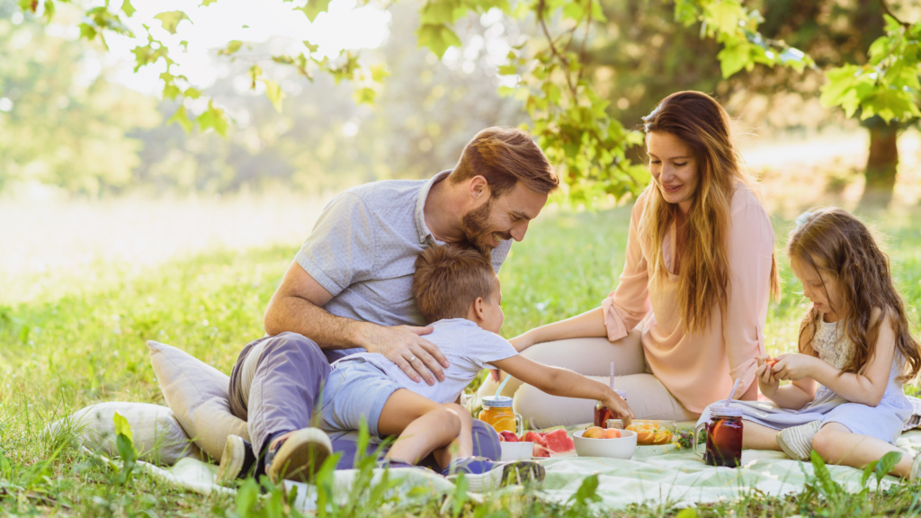 Stock photo from Canva by Zukovic at Getty Images of a family having a picnic in the park