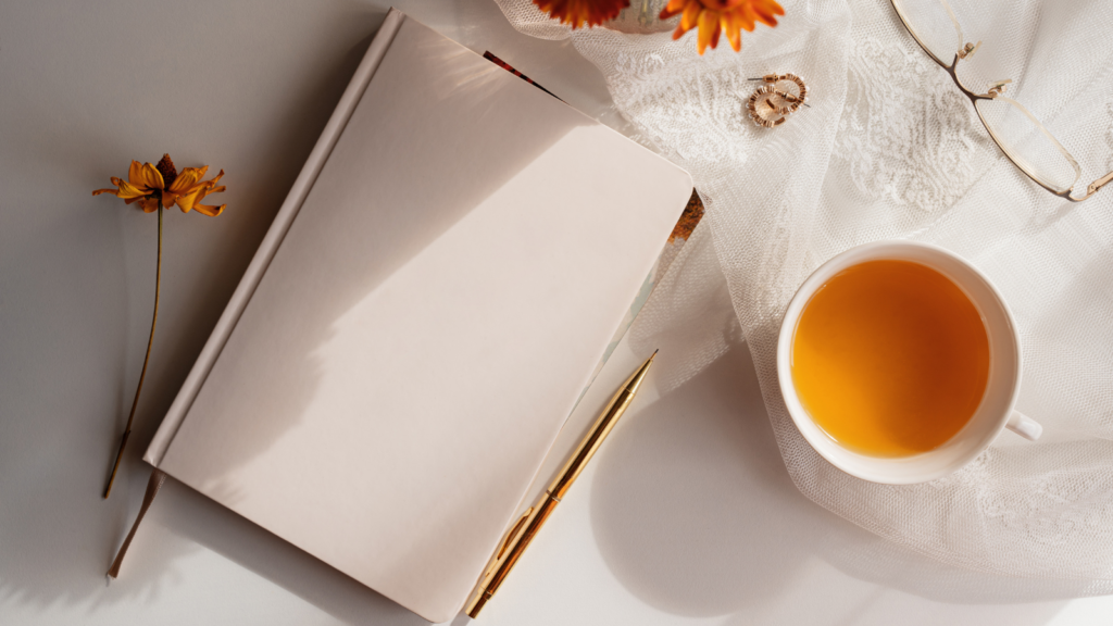 Stock photo from Canva by Zane Magone of a pink notebook on a white table