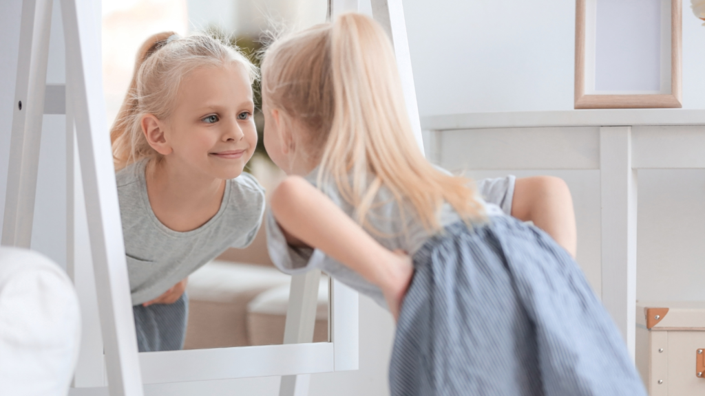 Stock photo from Canva by Pixelshot of a young girl looking in a mirror smiling 