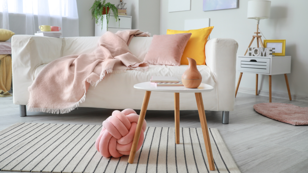 Stock photo from Canva by Pixelshot of a living room white couch with pink and yellow pillows