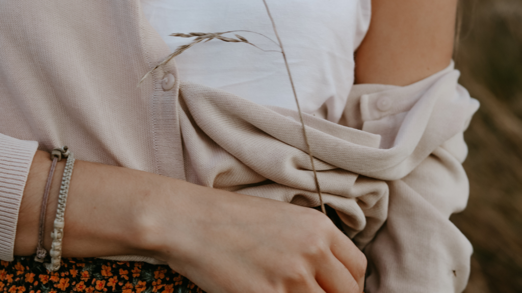 Stock photo from canva of a woman wearing a white cami top, lightweight brown cardigan and burnt orange skirt