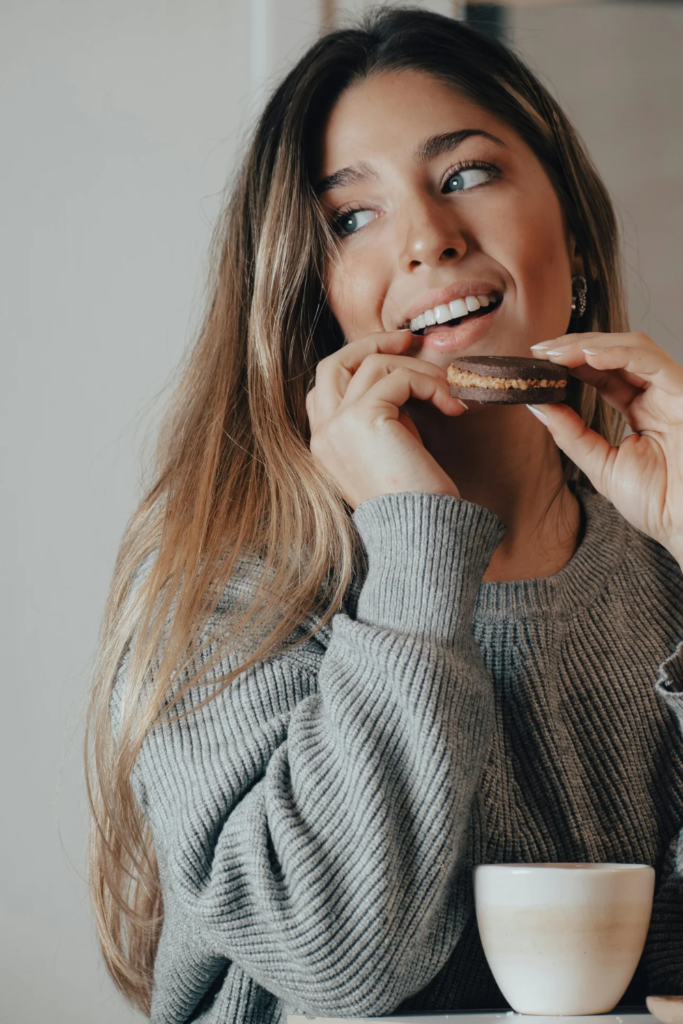 Stock photo from Canva of a woman smiling eating a protine bar