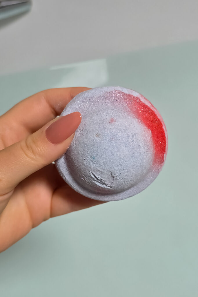 Close up photo of the Space Girl Bath Bomb from Lush being held in Ofaglasgowgirls hand over a bath.
